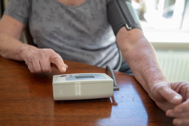 Eine ältere Seniorin überprüft ihren Blutdruck zu Hause im Gesundheitskonzept