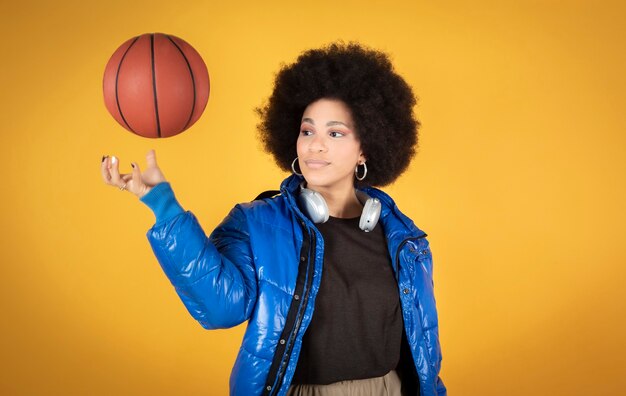 Eine Afro, gemischte, glückliche Frau lächelnd, im Studio einen Basketball haltend. Basketball-Spieler