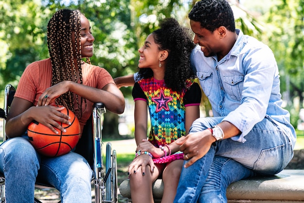 Eine Afroamerikanerin im Rollstuhl, die einen Tag im Park mit ihrer Familie genießt.