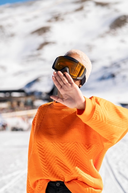 Eine afroamerikanische Frau, die im Winter eine Schneebrille auf einem schneebedeckten Berg trägt