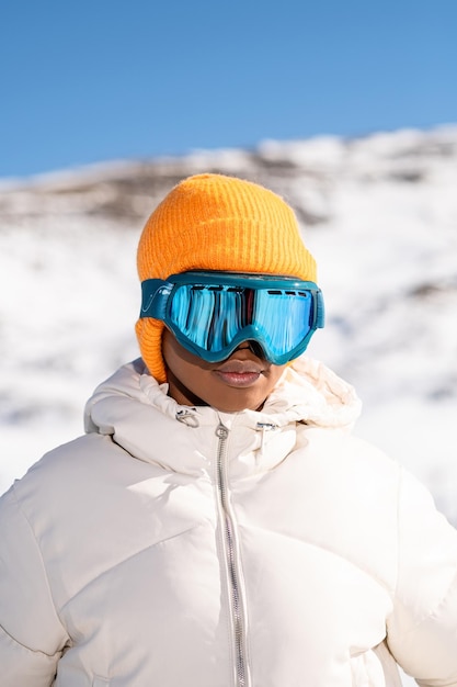 Eine afroamerikanische Frau, die im Winter eine Schneebrille auf einem schneebedeckten Berg trägt