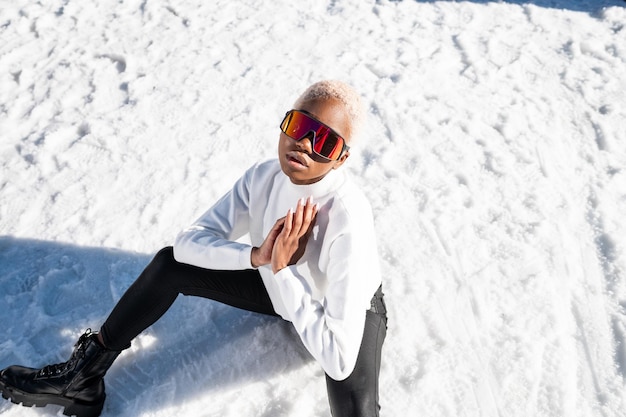 Eine afroamerikanische Frau, die im Winter eine Schneebrille auf einem schneebedeckten Berg trägt