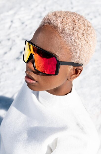 Eine afroamerikanische Frau, die im Winter eine Schneebrille auf einem schneebedeckten Berg trägt