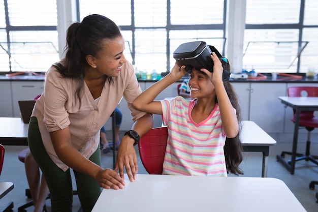 Eine afroamerikanische Lehrerin bringt einem Mädchen im Unterricht in der Schule die Verwendung eines VR-Headsets bei