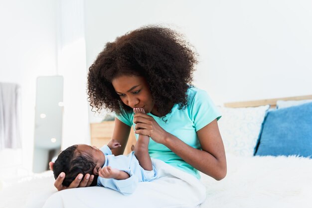 Foto eine afroamerikanische mutter küsst die füße ihres 1-monatigen neugeborenen mit einem glücklichen und liebevollen konzept für eine afroamerikanische familie und ein neugeborenes