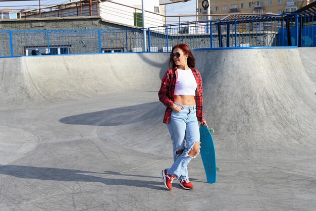 Eine aktive Frau mittleren Alters fährt mit einem Skateboard auf einer leeren Straße oder Autobahn Eine gewöhnliche Stadtfrau, die sich nach der Arbeit auf einem Skateboard entspannt Das Konzept eines modernen Lebensstils