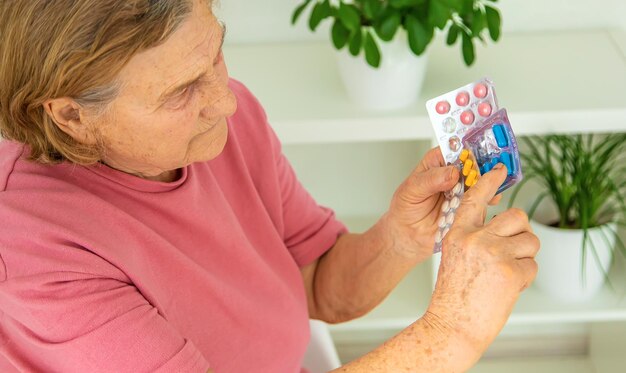 Eine alte Frau hält Pillen in ihren Händen Selektiver Fokus