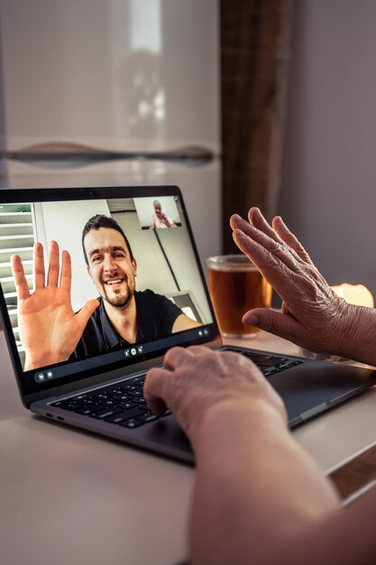 Eine alte Frau kommuniziert mit ihrem Sohn per Videoverbindung über einen Laptop