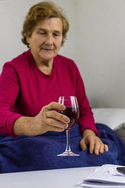Eine alte Frau trinkt Wein zu Hause Selektiver Fokus