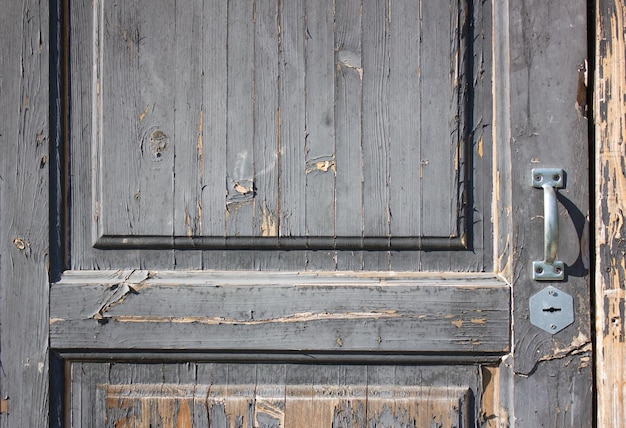 Eine alte heruntergekommene Holztür mit einem Griff. Die Eingangstür ist alt und verlassen