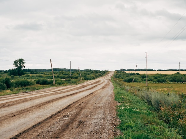 Eine alte Landstraße Die Straße ist ohne Asphalt Strommasten und bedecktem Himmel