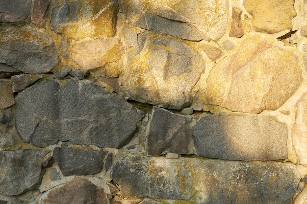 Eine alte Mauer aus Granitsteinen unterschiedlicher Größe als Hintergrund.