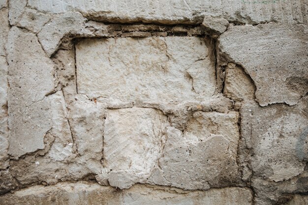 Eine alte Mauer, die einstürzt, Ziegelsteine sichtbar, strukturiert.