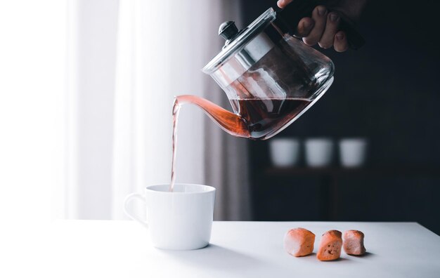 Eine anonyme Hand füllt Kaffee aus einer Kanne mit Kopierraum in die Tasse