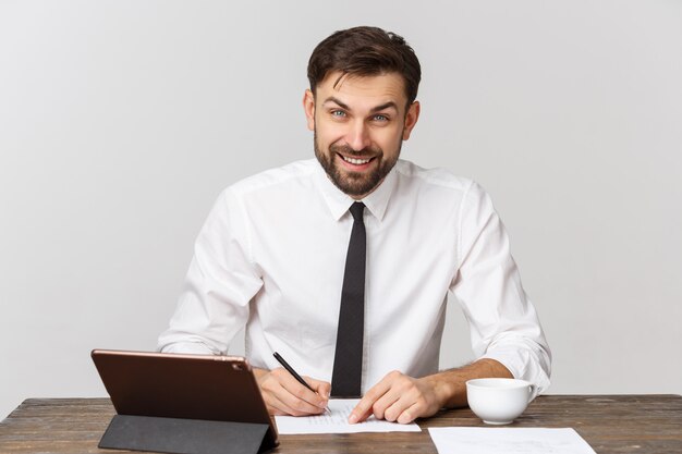 Eine Ansicht eines beschäftigten Geschäftsmannes, der ein Dokument im Büro gegen weißen Hintergrund unterschreibt