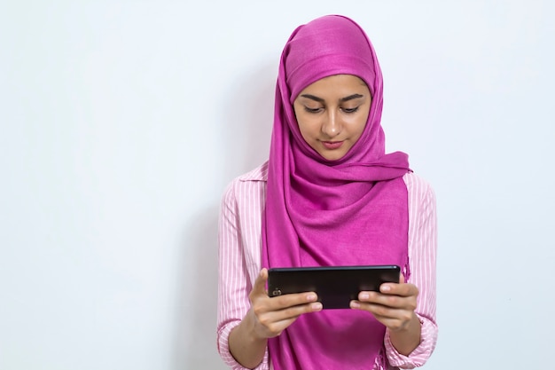 Eine arabische junge Frau hält eine Tablette in ihren Händen