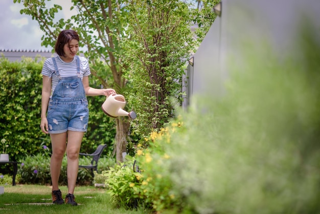 Eine Asiatin gießt Pflanzen im Garten