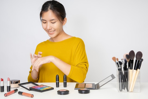 Eine asiatische Bloggerin, die ein Video von sich selbst mit einem orangefarbenen Lippenstift in einem Studio dreht.