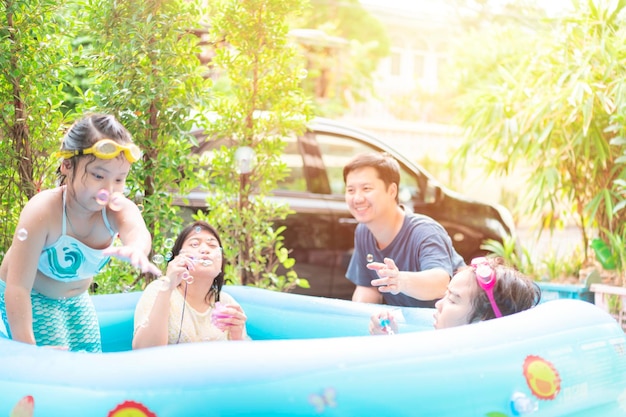 Eine asiatische Familie spielt in einem aufblasbaren Pool, indem sie Spaß beim Spielen hat. Seifenblasen. Liebe und Wärme füreinander in der Familie