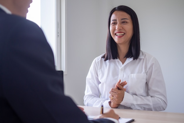 Eine asiatische Frau lächelte und entspannte sich und interviewte eine Führungskraft. Der Personalmanager führt ein Vorstellungsgespräch mit den Bewerbern im Büro.