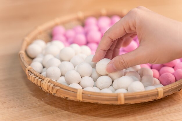 Eine asiatische Frau macht Tang Yuan, Yuan Xiao, chinesische traditionelle Lebensmittelreisknödel in Rot und Weiß für Mondneujahr, Winterfest, Nahaufnahme.