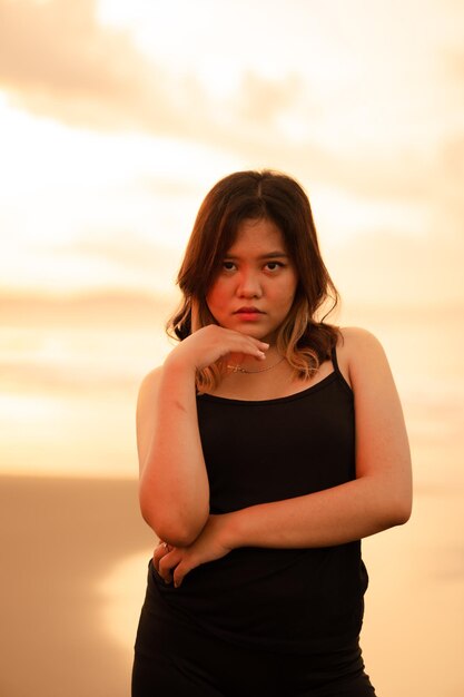 Eine asiatische Frau mit blonden Haaren und einem schwarzen Kleid, die einsam am Strand hängt, während sie Bali besucht