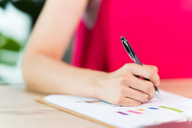 Eine asiatische Frau mittleren Alters, die einen Vertrag unterschreibt und im Büro arbeitet