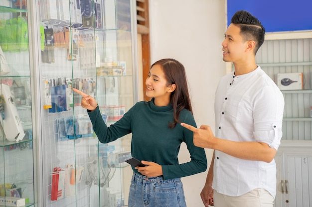 Eine asiatische Frau und ein Mann, die auf eine Glasvitrine zeigen
