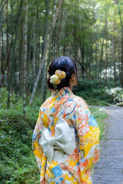 Foto eine asiatische frau versucht, einen japanischen kimono im bambuswald zu tragen