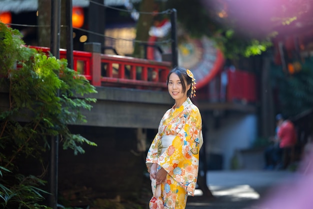 Eine asiatische Frau versucht, einen japanischen Kimono mit dem traditionellen japanischen Dorfhintergrund zu tragen