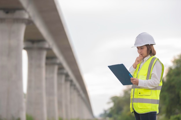 Foto eine asiatische ingenieurin arbeitet auf der baustelle einer autobahnbrücke.