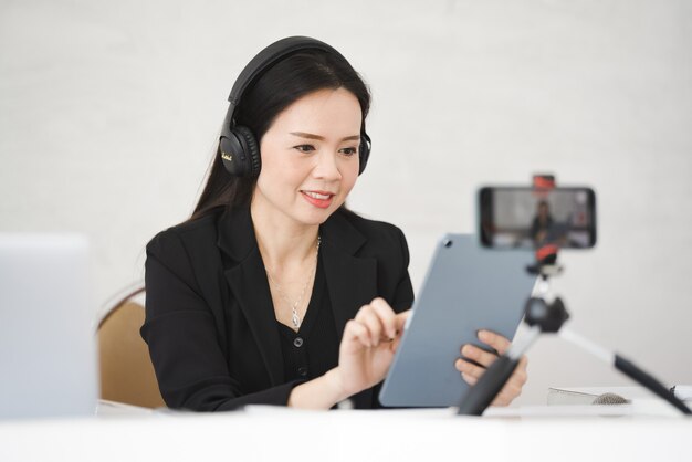 Eine asiatische Lehrerin mittleren Alters lebt online mit dem Smartphone an der Universität