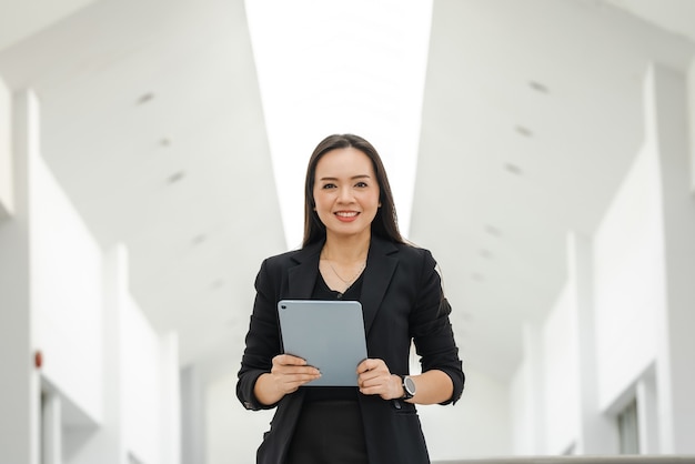 Eine asiatische Lehrerin mittleren Alters mit einem Tablet an der Universität