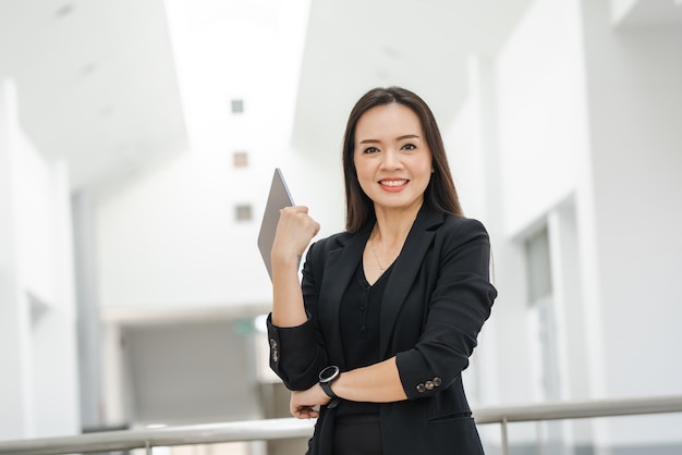 Eine asiatische Lehrerin mittleren Alters mit einem Tablet an der Universität