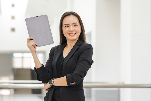 Eine asiatische Lehrerin mittleren Alters mit einem Tablet an der Universität