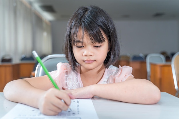 Eine asiatische Schülerin konzentriert sich auf das Prüfungspapier in der Klasse