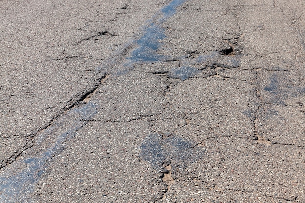 Eine Asphaltstraße mit vielen Löchern und Schlaglöchern