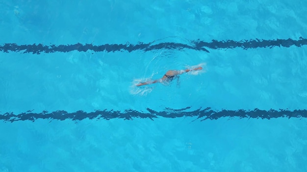 Eine Athletin führt synchronisierte Schwimmroutinen in einem Außenpool aus der Luft aus