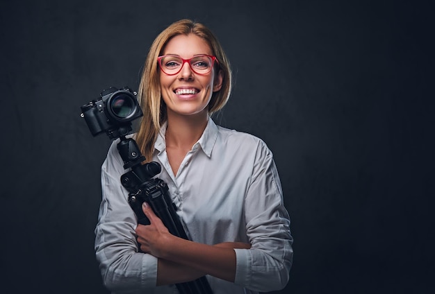 Eine attraktive blonde Fotografin, die mit einer professionellen Kamera auf einem Stativ fotografiert.