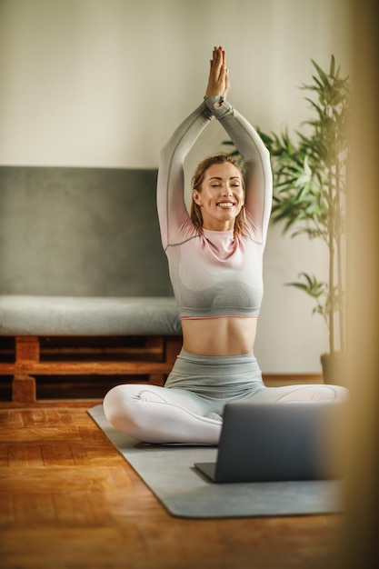 Eine attraktive junge Frau mit Laptop, während sie tagsüber Yoga in einem Studio praktiziert.