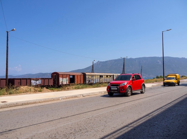 Eine Autobahn mit Autos auf dem Hintergrund verlassener Eisenbahnwaggons in Griechenland