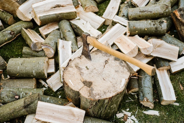 Eine Axt auf einem Baumstamm neben einem gehackten Brennholz