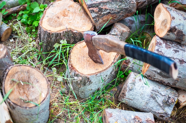 Eine Axt zum Hacken von Holz steckt in einem Baumstamm Beschaffung von Brennstoff zum Heizen des Hauses im Winter