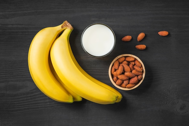 Eine Banane mit Mandeln und Milch auf hölzernem Hintergrund.