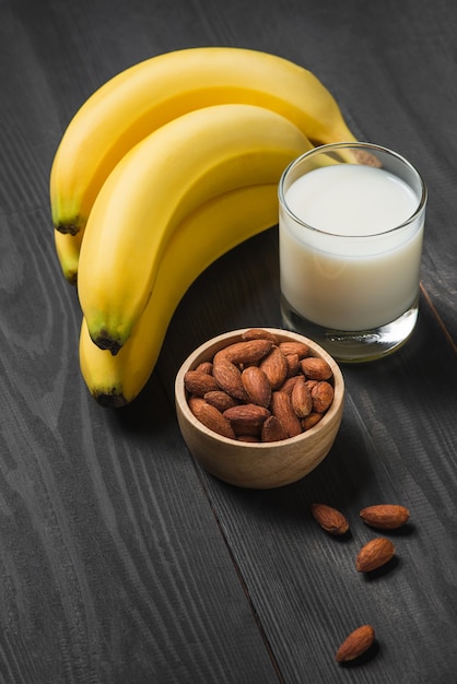 Eine Banane mit Mandeln und Milch auf hölzernem Hintergrund.