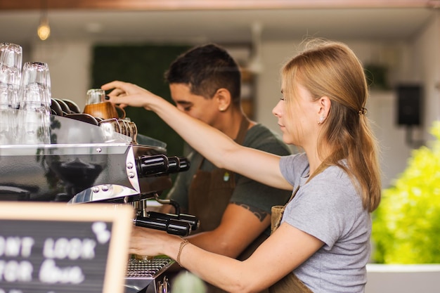 Eine Barista der mittleren Altersfrau, die Kaffee in einer Maschine kocht