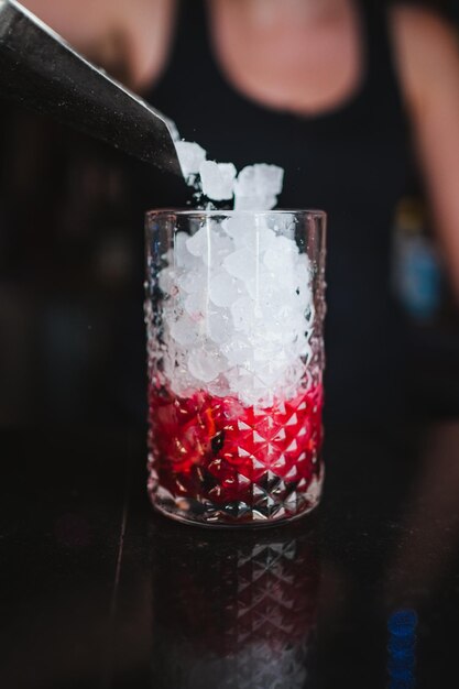 Eine Barkeeperin gießt mit einer Schaufel zerstoßenes Eis in ein Glas, um in einem Pub einen Beeren-Mojito zuzubereiten