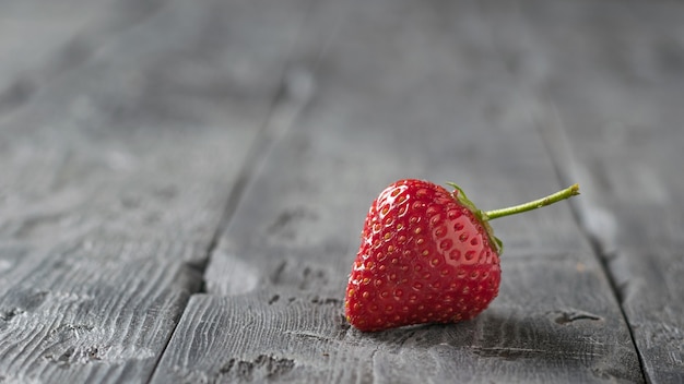 Eine Beere reife Erdbeeren auf einem schwarzen Holztisch. Süßes Beerendessert.