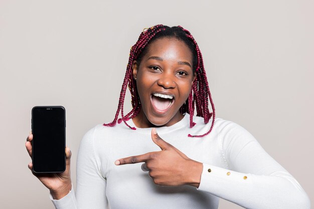 Eine begeisterte afroamerikanische Frau hält ein Handy mit schwarzem Bildschirm in der Hand und zeigt