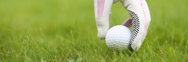 Eine behandschuhte Hand einer Frau bringt einen Golfball in Position helles saftiges Gras auf einem Golfplatz